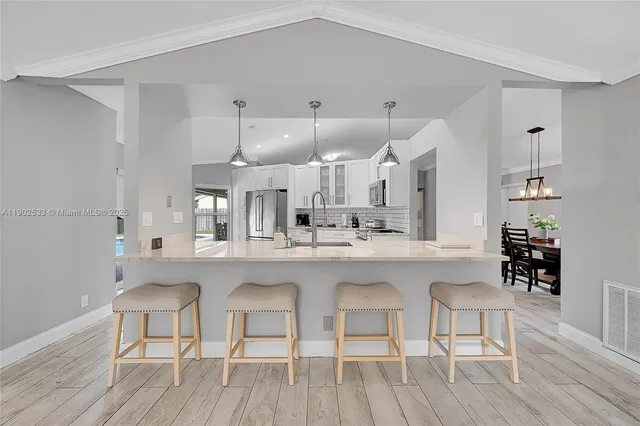 a kitchen with cabinets a sink dishwasher a dining table and chairs with wooden floor