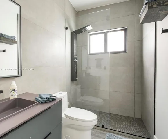 a bathroom with a granite countertop sink a toilet and shower