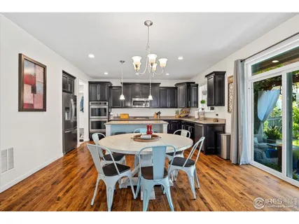 a open kitchen with stainless steel appliances kitchen island granite countertop a table chairs and a refrigerator
