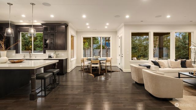 a large living room with stainless steel appliances kitchen island granite countertop a stove a sink a large island with chairs and wooden floor