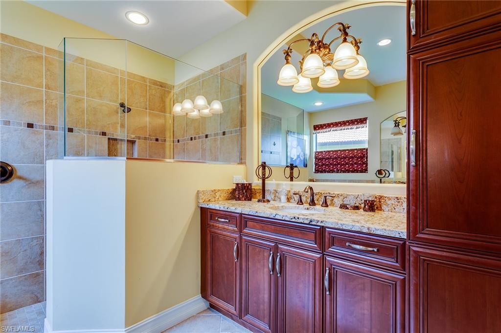 7771 Cottesmore Drive Naples, FL 34113 - Photo 24 of 32 a bathroom with a sink a mirror and a shower