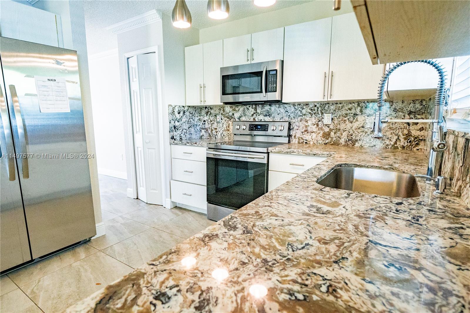 Shenandoah Davie, FL 33325 - Photo 49 of 61 a kitchen with stainless steel appliances granite countertop a refrigerator a stove a sink and a microwave