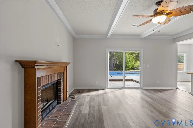 an empty room with wooden floor fireplace and windows