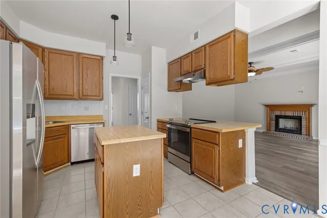 a kitchen with stainless steel appliances granite countertop a stove top oven a refrigerator a sink and dishwasher with white cabinets