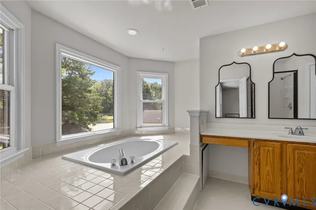 a spacious bathroom with a tub double sink window and mirror