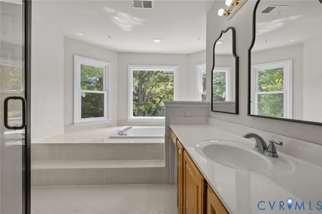 a bathroom with double vanity sink a mirror and a bathtub