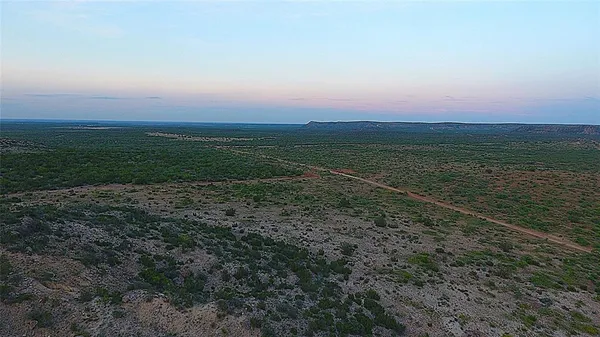 a view of a dry yard with mountains in the background