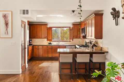 a kitchen with stainless steel appliances granite countertop a stove a sink dishwasher and a microwave oven with cabinets