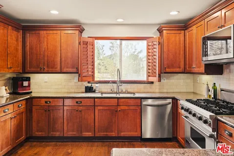 a kitchen with granite countertop a stove top oven microwave and cabinets