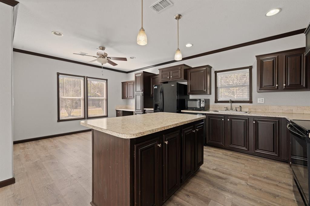 9419 Hilltop Street Rio Vista, TX 76093 - Photo 14 of 40 a kitchen with a stove a sink dishwasher a refrigerator and cabinets with wooden floor