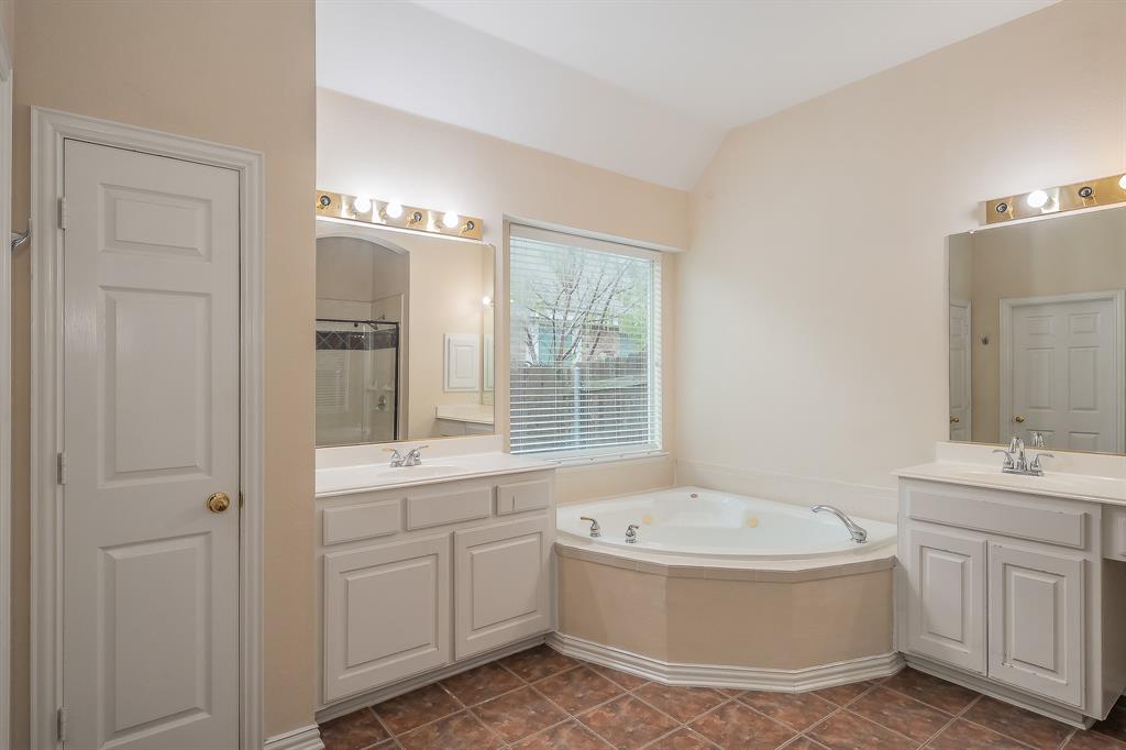 2306 Bear Run Road Arlington, TX 76001 - Photo 24 of 40 Bathroom with two vanities, a shower stall, a bath, vaulted ceiling, and dark tile patterned flooring