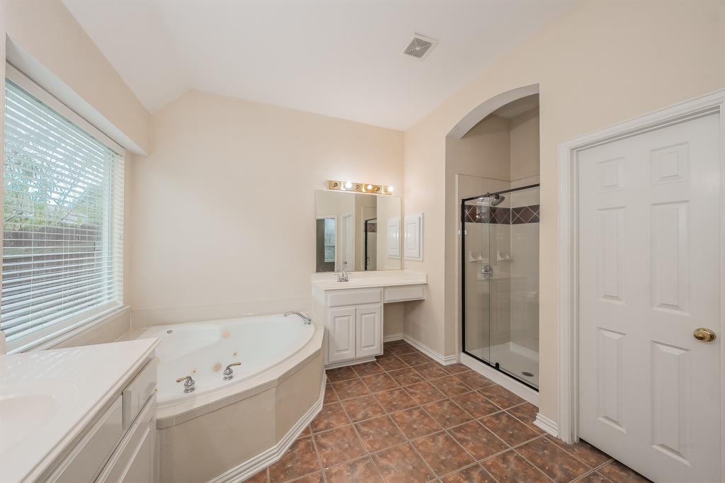 2306 Bear Run Road Arlington, TX 76001 - Photo 25 of 40 Bathroom featuring two vanities, a stall shower, a jetted tub, dark tile patterned flooring, and lofted ceiling