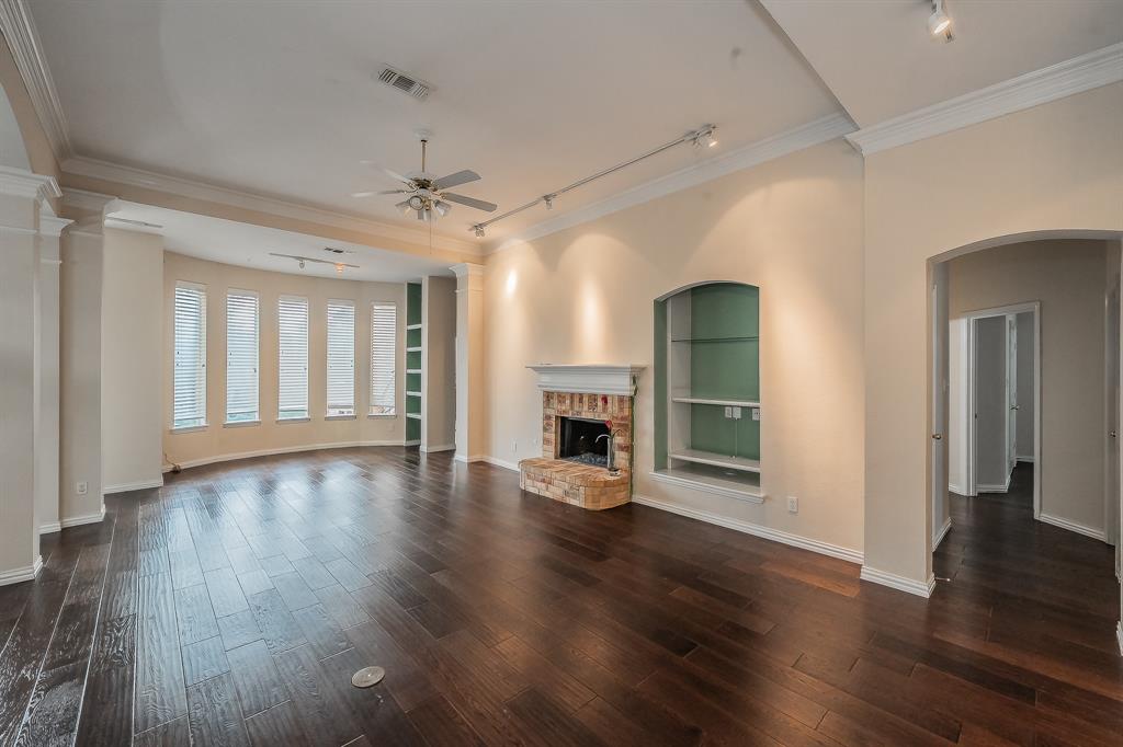 2306 Bear Run Road Arlington, TX 76001 - Photo 29 of 40 Unfurnished living room featuring rail lighting, ornamental molding, a ceiling fan, built in shelves, and dark wood finished floors