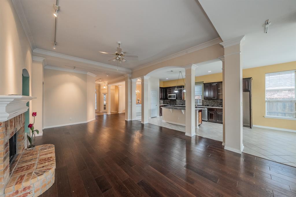 2306 Bear Run Road Arlington, TX 76001 - Photo 31 of 40 Unfurnished living room with decorative columns, a fireplace, crown molding, dark wood-style flooring, and ceiling fan