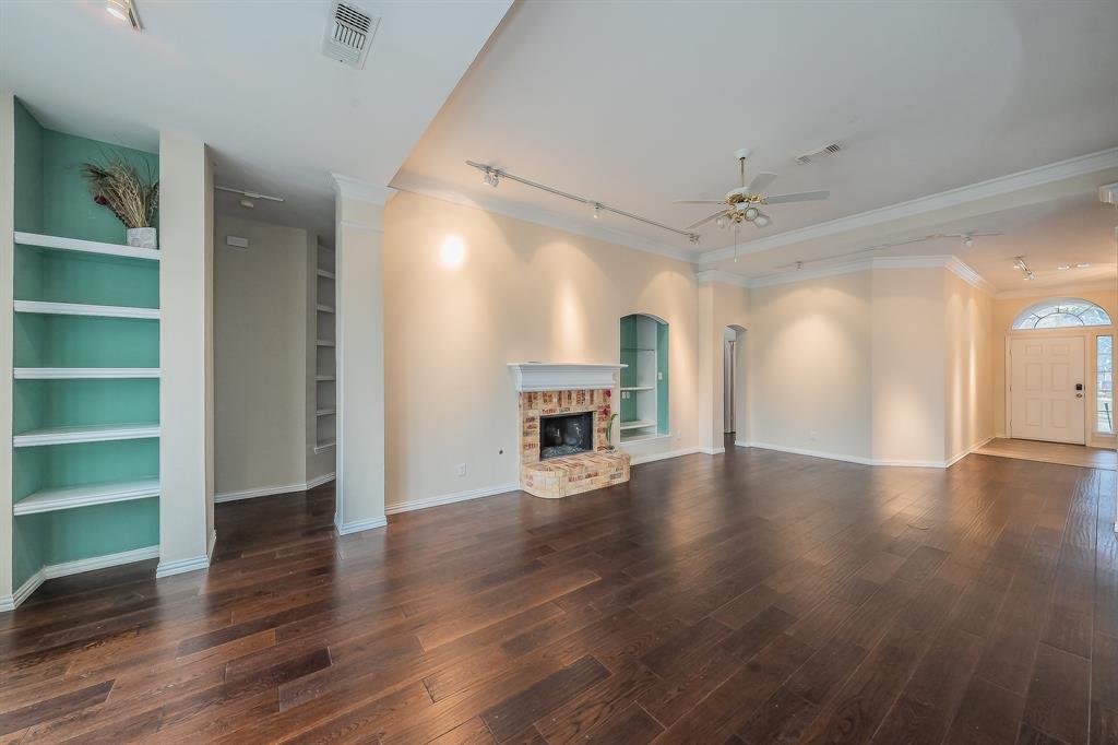 2306 Bear Run Road Arlington, TX 76001 - Photo 32 of 40 Unfurnished living room with track lighting, built in shelves, dark wood-type flooring, a brick fireplace, and ornamental molding