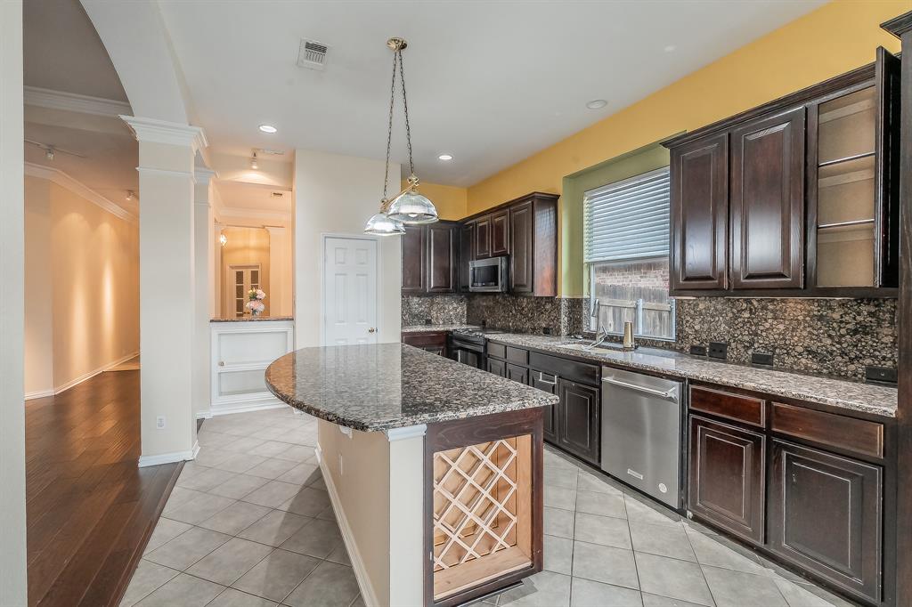 2306 Bear Run Road Arlington, TX 76001 - Photo 33 of 40 Kitchen with dark brown cabinets, dark stone countertops, light tile patterned floors, decorative light fixtures, and crown molding