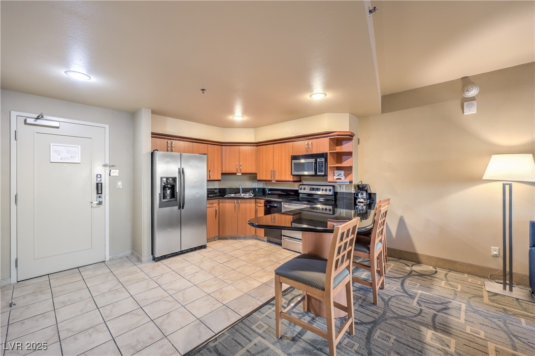 211 East Flamingo Road, Unit 1508 Las Vegas, NV 89169 - Photo 12 of 40 Kitchen with appliances with stainless steel finishes, brown cabinetry, open shelves, light tile patterned floors, and a peninsula