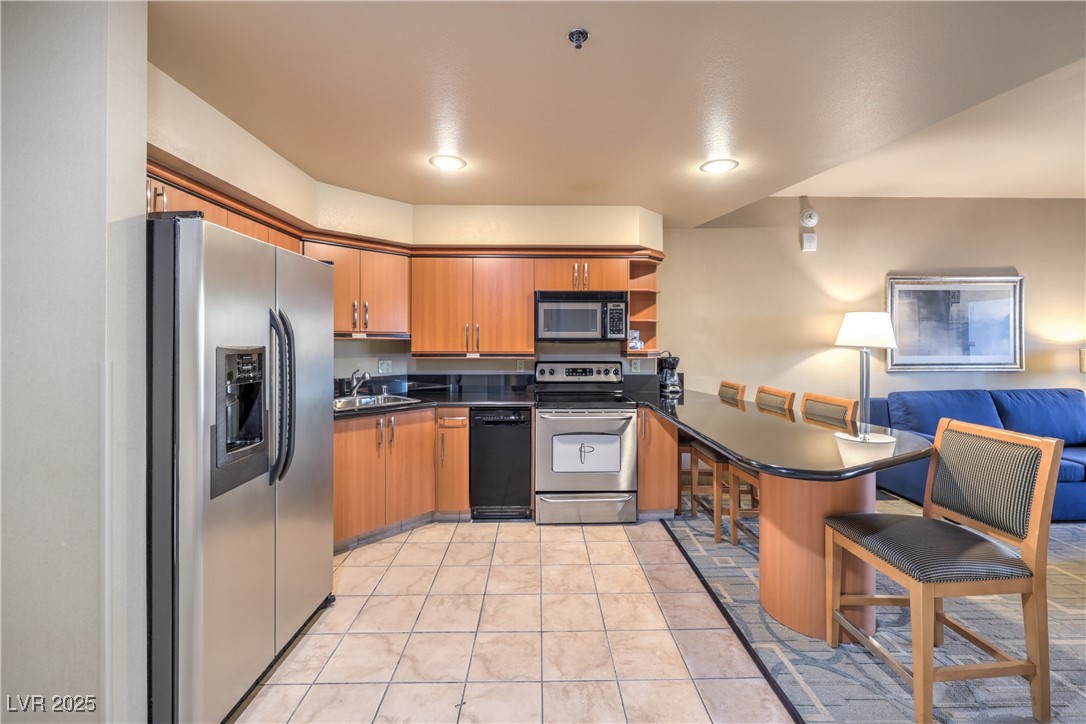 211 East Flamingo Road, Unit 1508 Las Vegas, NV 89169 - Photo 13 of 40 Kitchen featuring a kitchen breakfast bar, a peninsula, stainless steel appliances, brown cabinets, and open shelves