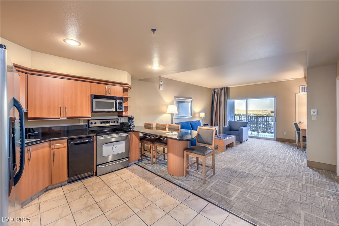 211 East Flamingo Road, Unit 1508 Las Vegas, NV 89169 - Photo 40 of 40 Kitchen with a breakfast bar, stainless steel appliances, a peninsula, open floor plan, and dark stone counters