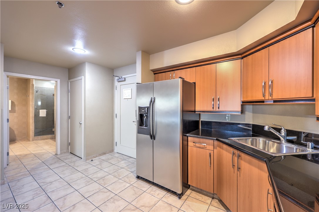 211 East Flamingo Road, Unit 1508 Las Vegas, NV 89169 - Photo 15 of 40 Kitchen featuring stainless steel refrigerator with ice dispenser, brown cabinets, and dark stone counters