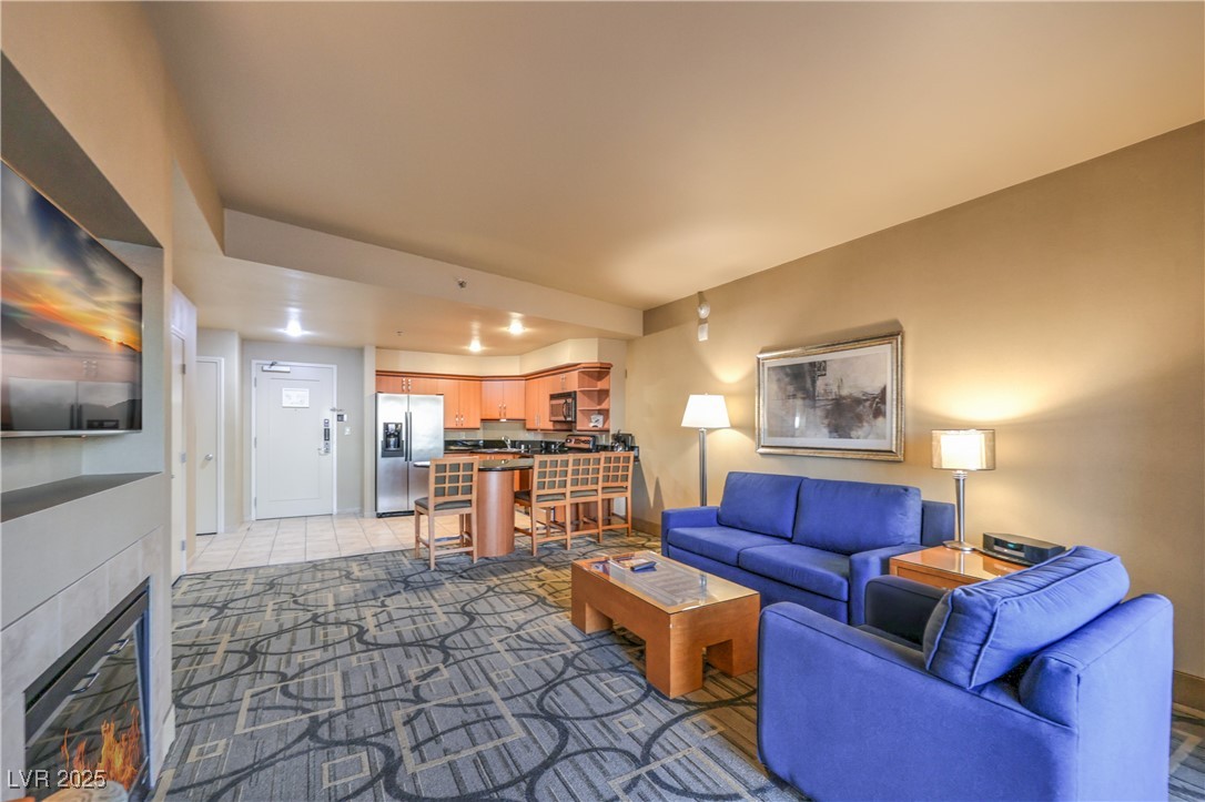 211 East Flamingo Road, Unit 1508 Las Vegas, NV 89169 - Photo 7 of 40 Living area featuring a glass covered fireplace, dark tile patterned flooring, and dark colored carpet