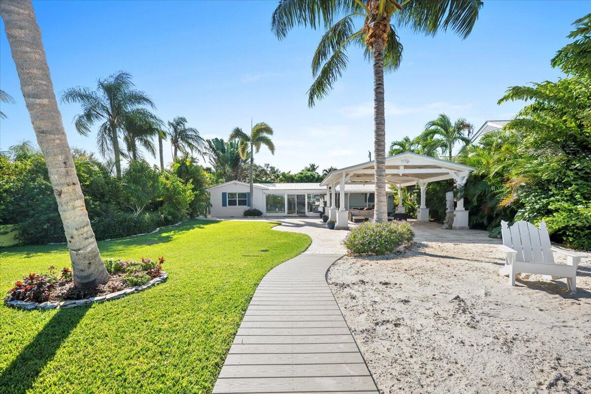 119 Elsa Road Jupiter, FL 33477 - Photo 12 of 38 a view of a house with a yard patio and a swimming pool