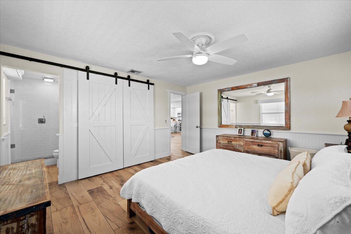 119 Elsa Road Jupiter, FL 33477 - Photo 29 of 38 a bedroom with a large bed and a chandelier