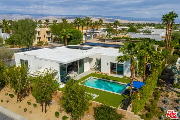 an aerial view of a house with swimming pool and large trees
