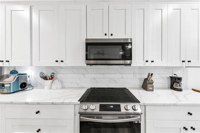 a kitchen with white cabinets and appliances