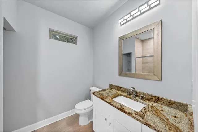a bathroom with a granite countertop sink toilet and mirror