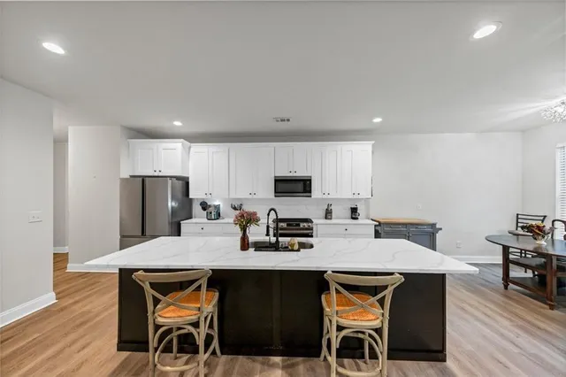 a kitchen with stainless steel appliances granite countertop a table chairs stove refrigerator and cabinets