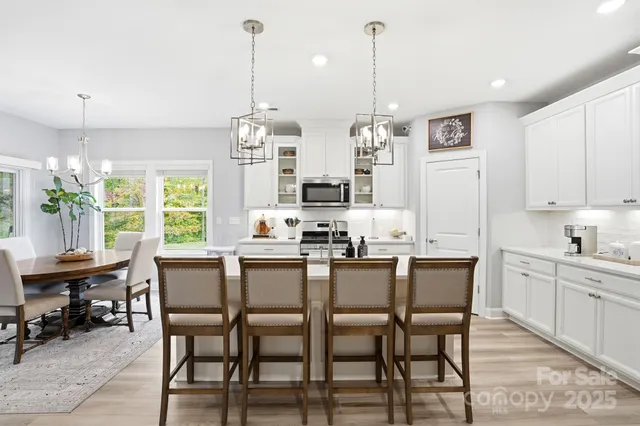 a kitchen with stainless steel appliances a dining table chairs refrigerator and microwave