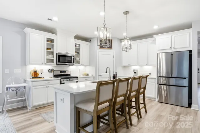 a kitchen with stainless steel appliances granite countertop white cabinets and a stove top oven