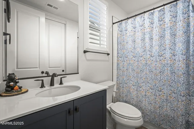 a bathroom with a granite countertop sink toilet and mirror