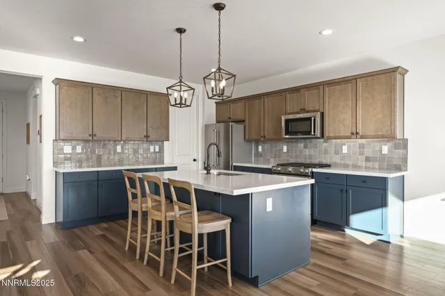 a kitchen with stainless steel appliances granite countertop a stove top oven a sink dishwasher a dining table and chairs with wooden floor