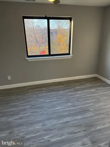 a view of a room has wooden floor and a window