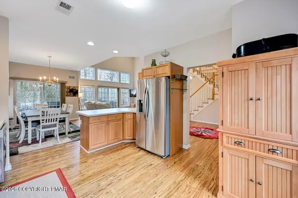 a large kitchen with stainless steel appliances granite countertop a refrigerator a sink dishwasher a stove and a dining table with wooden floor