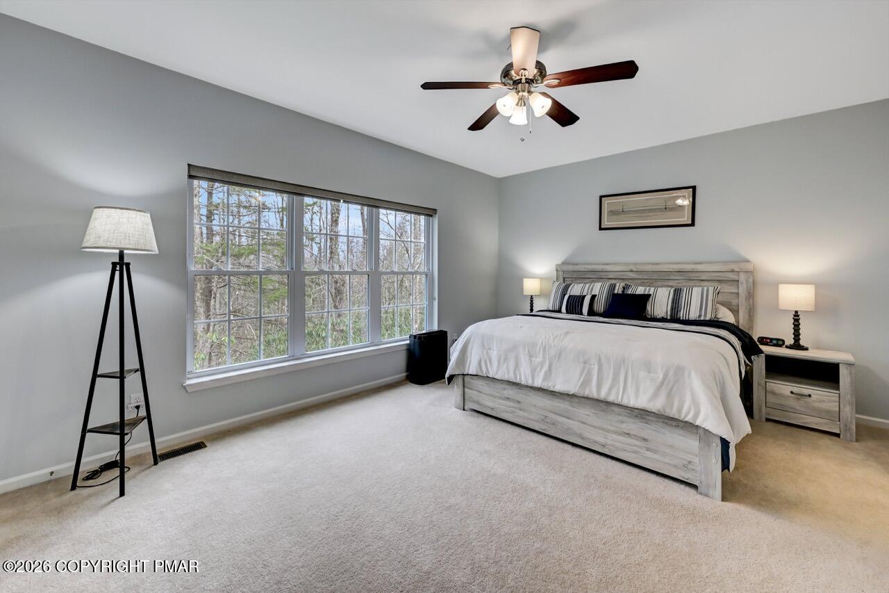 134 Skytop Road Long Pond, PA 18334 - Photo 13 of 48 a spacious bedroom with a bed a chandelier and a window