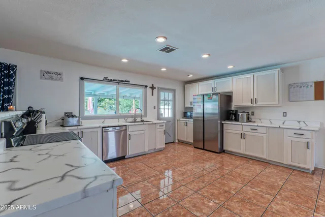 a large kitchen with kitchen island a sink dishwasher stove and white cabinets