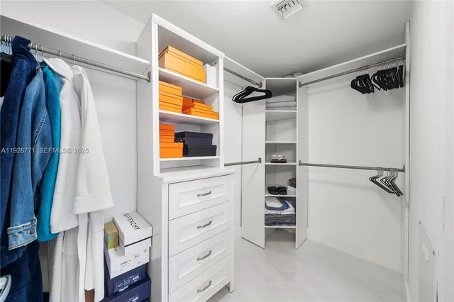 a view of walk in closet with clothes and shoes