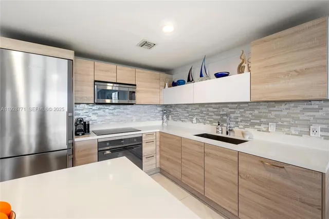 a kitchen with stainless steel appliances a sink a stove a refrigerator and cabinets