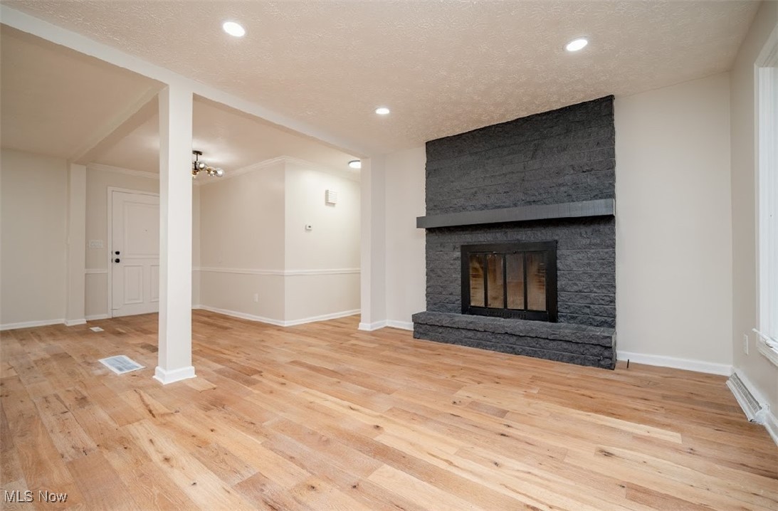 6006 Tippecanoe Road Canfield, OH 44406 - Photo 9 of 35 Unfurnished living room featuring wood-type flooring, a large fireplace, baseboards, recessed lighting, and a textured ceiling