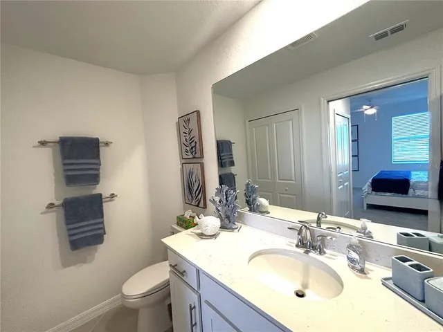 a bathroom with a granite countertop sink toilet and mirror