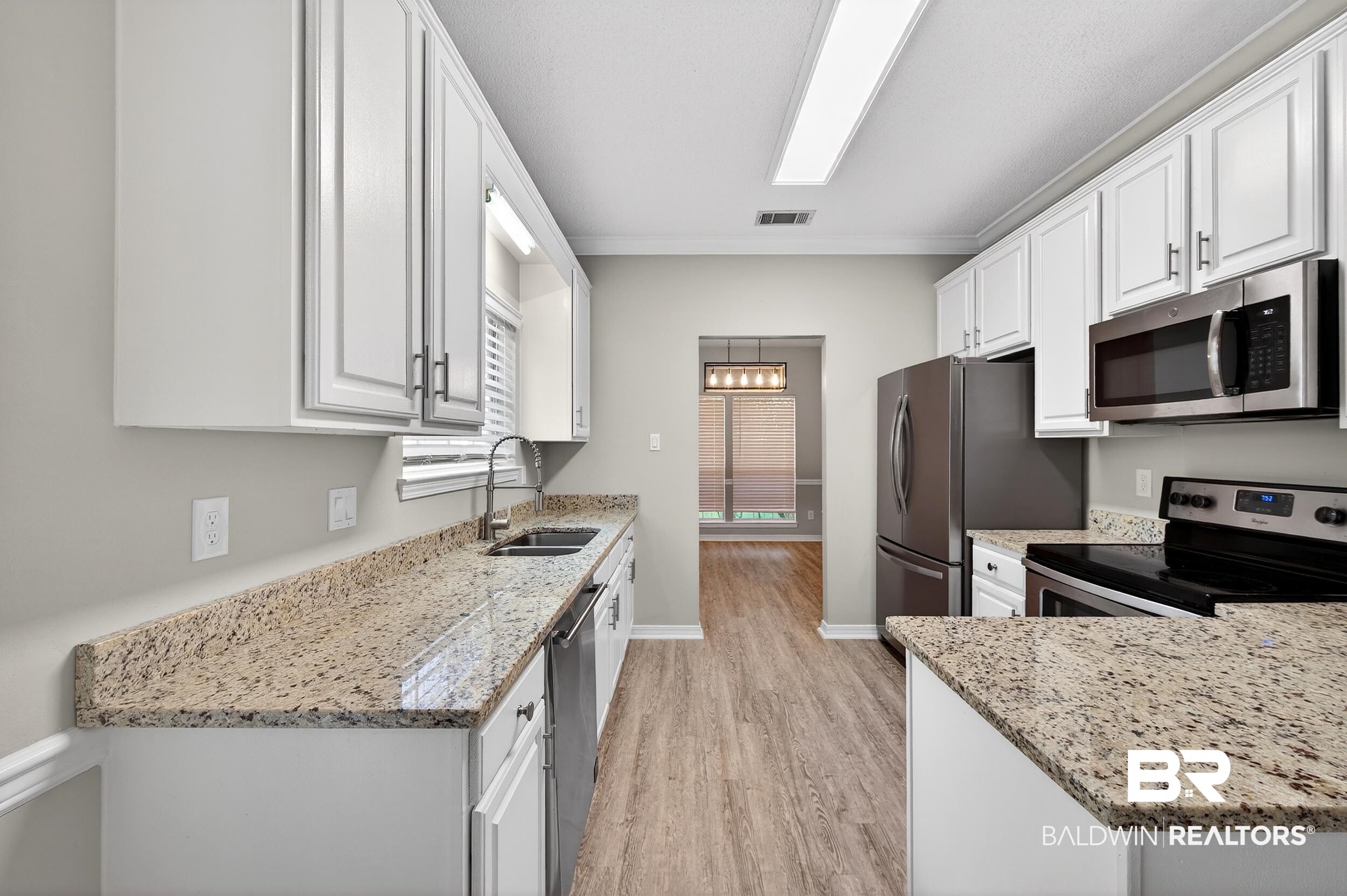 7050 Highpointe Place West Daphne, AL 36527 - Photo 19 of 66 Kitchen with light stone countertops, stainless steel appliances, white cabinets, light wood-style floors, and crown molding