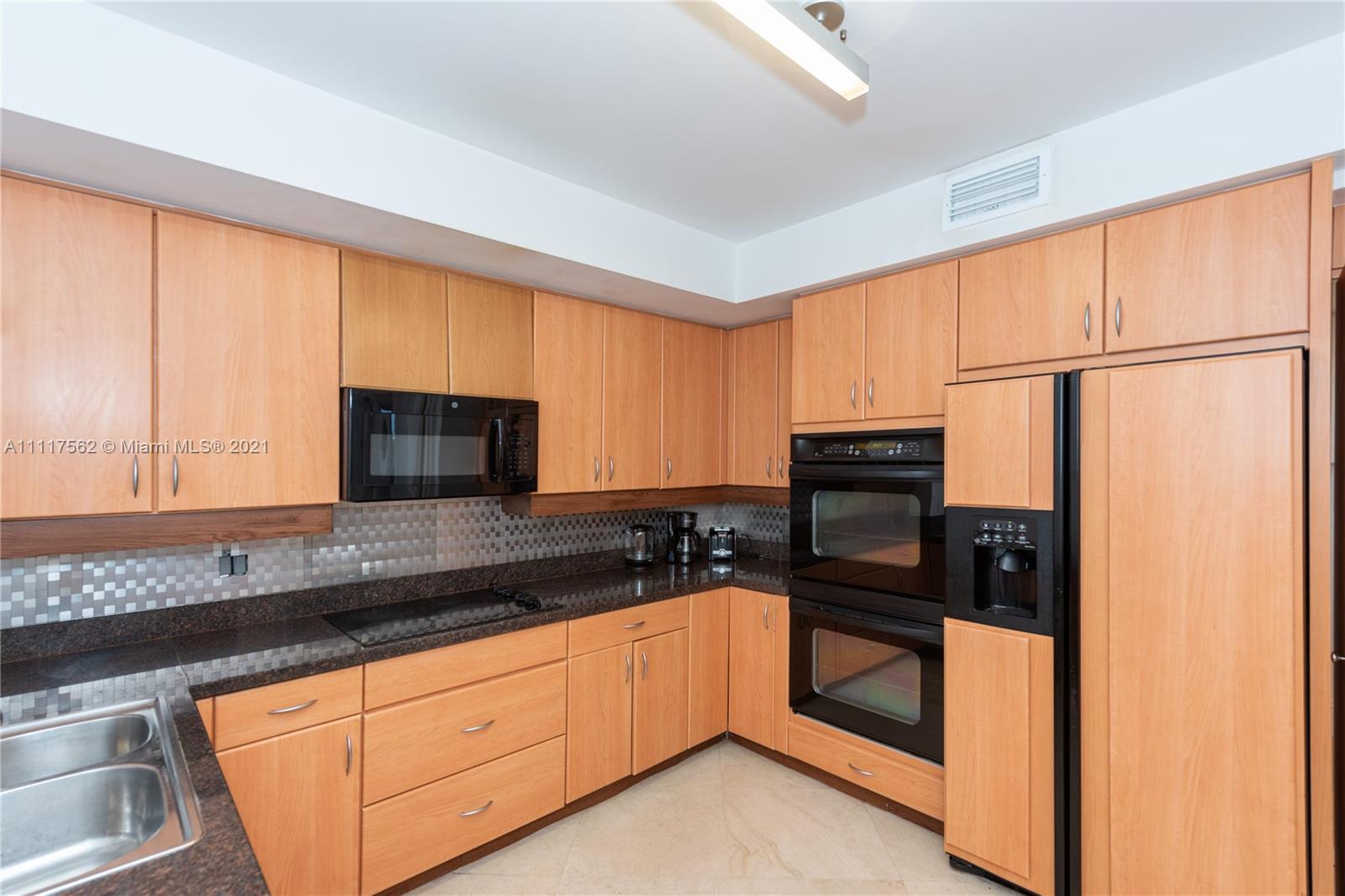 765 Crandon Boulevard, Unit 504 Key Biscayne, FL 33149 - Photo 10 of 46 a kitchen with stainless steel appliances granite countertop a stove a sink and a microwave
