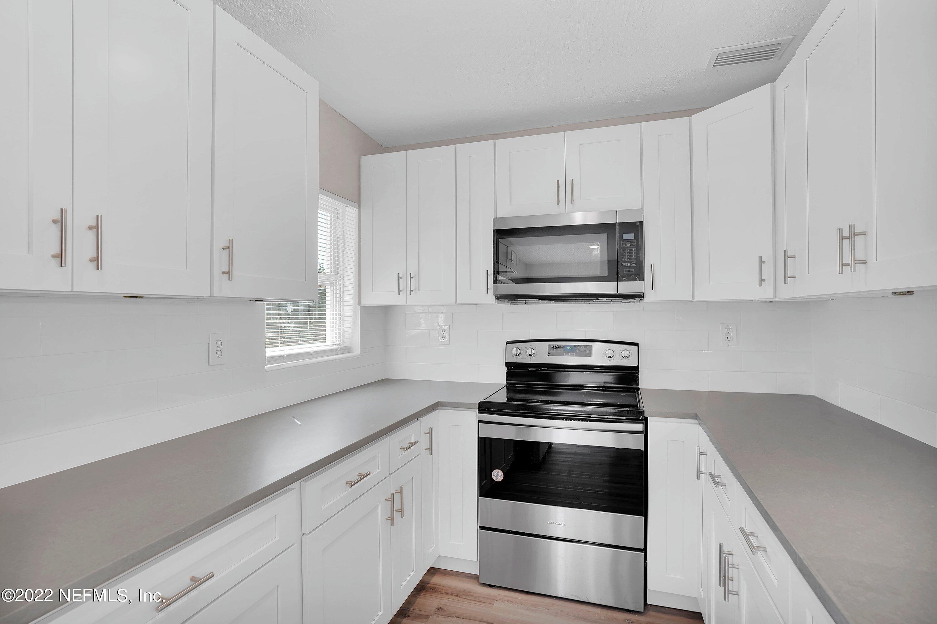 6631 Champlain Road Jacksonville, FL 32208 - Photo 13 of 25 a kitchen with white cabinets and stainless steel appliances
