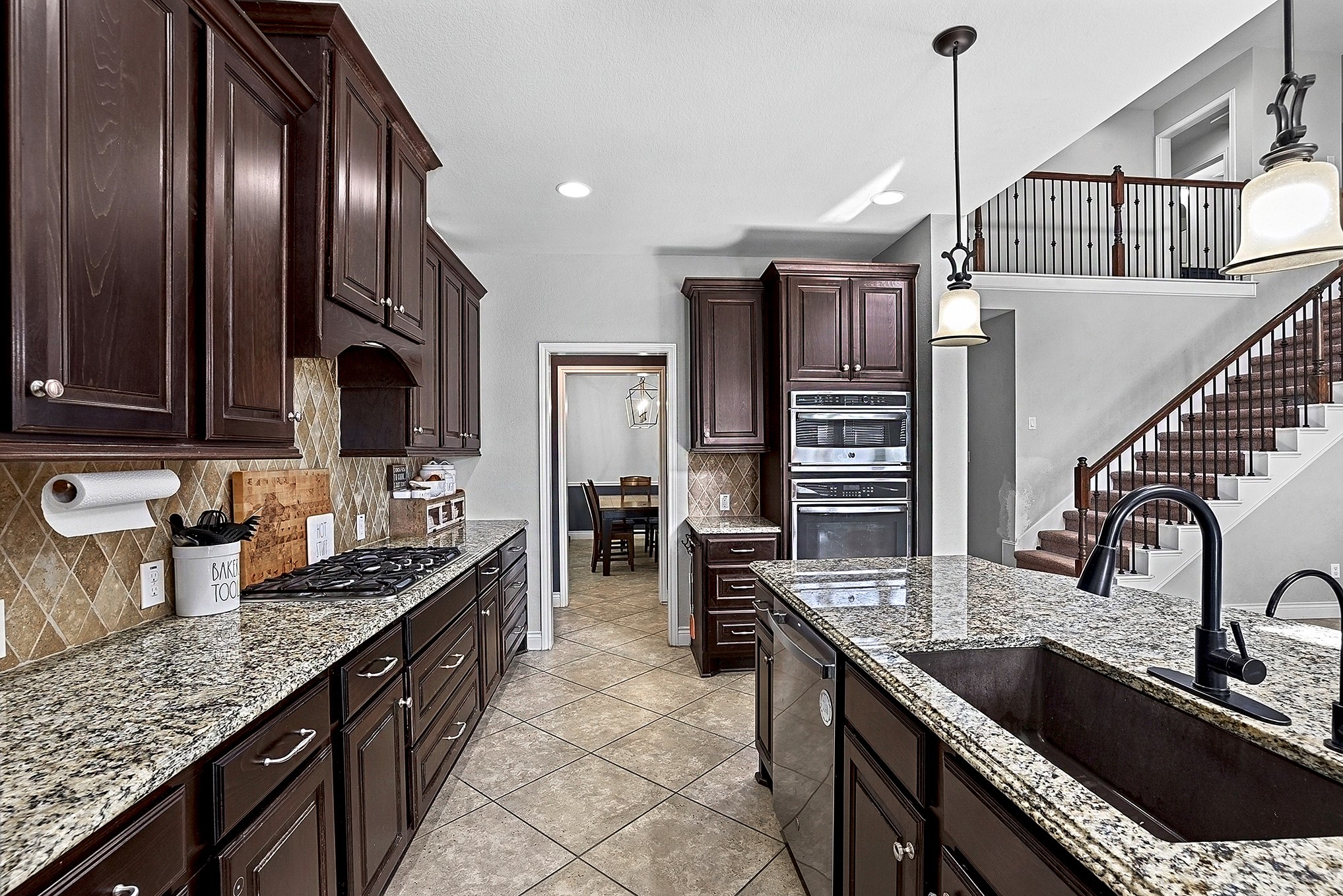 2951 Bobby Jones Road Katy, TX 77494 - Photo 16 of 50 View from the large kitchen island showcasing the farmhouse sink and spacious breakfast bar seating. Through the butler’s pantry, you can see the formal dining room, creating a convenient and connected flow between the kitchen and dining areas.