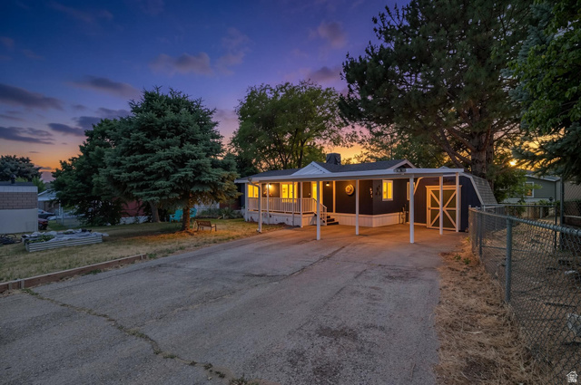 271 Mindella Way Layton, UT 84041 - Photo 1 of 27 Exterior featuring a covered porch with white railings, a carport, and a detached shed with barn-style doors