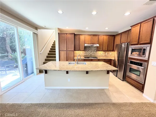 a view of kitchen with stainless steel appliances granite countertop a stove and a refrigerator