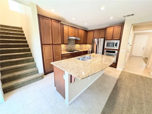 a kitchen with stainless steel appliances granite countertop a refrigerator a stove and a sink with wooden floor